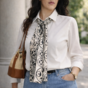 Dettaglio del Foulard Dea in twill di seta di gelso annodato al collo, indossato sopra una camicia bianca per un look elegante e senza tempo.