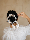 Scatto di spalle della modella che indossa lo scrunchie in raso Phlegráia su uno chignon alto, evidenziando come l'accessorio renda sofisticata l'acconciatura.
